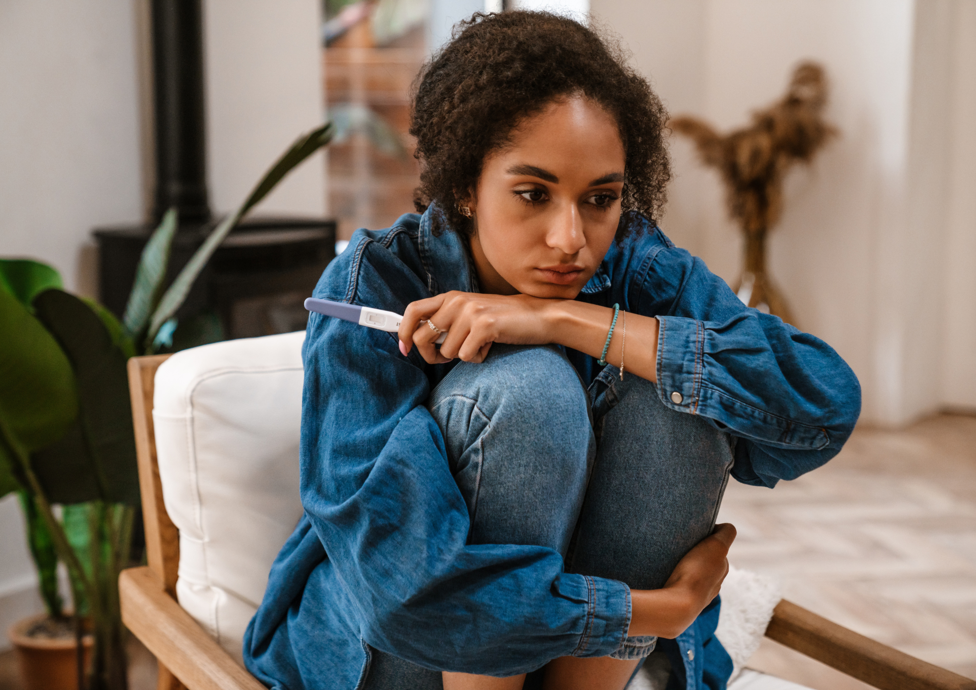 Femme regard perdu et triste avec un teste de grossesse a la main. Accompagnement des mères et future parents.